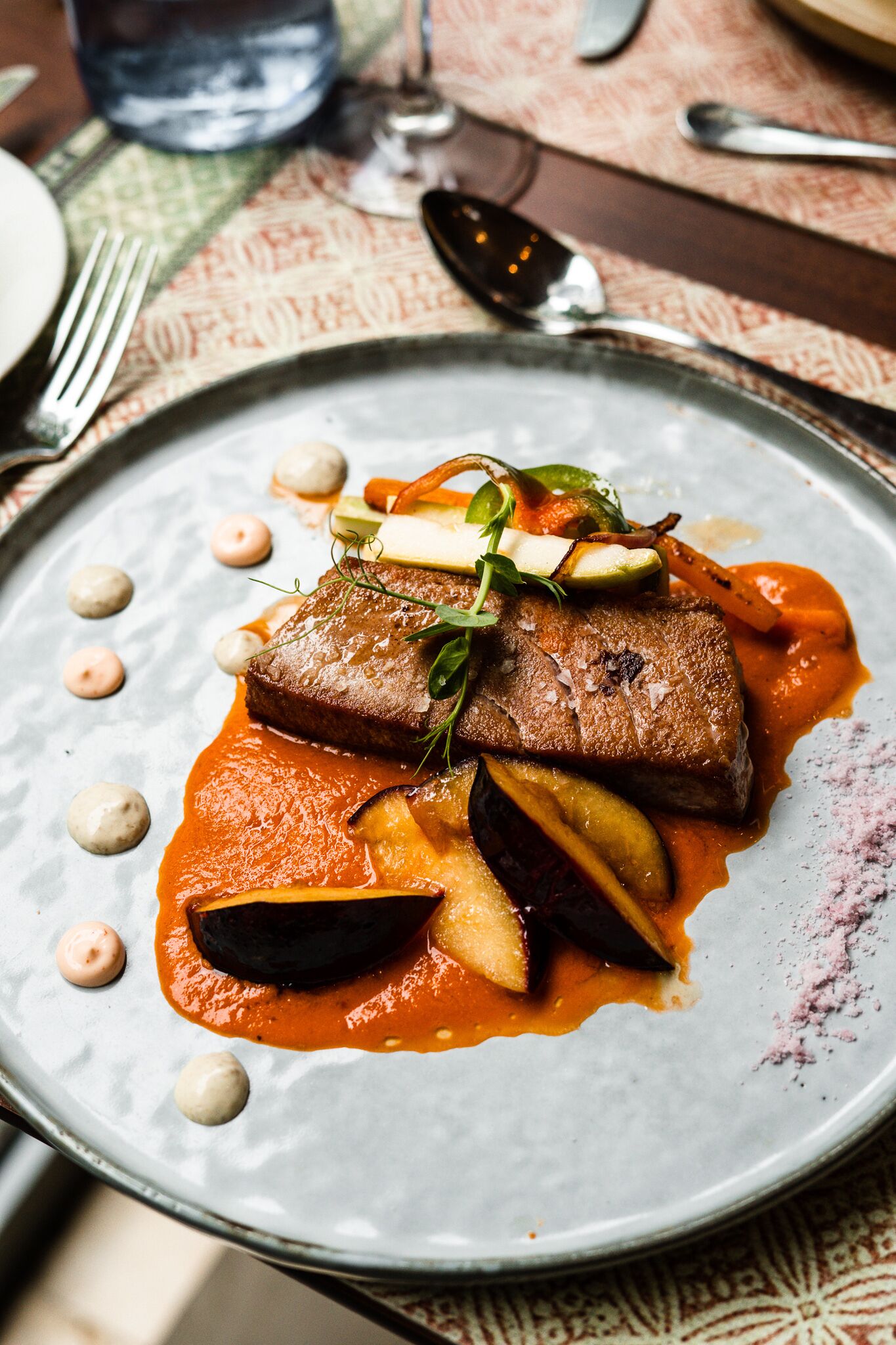 A plate of food with a piece of meat, vegetables, and sauce.