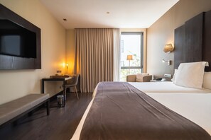 A hotel room with a bed, a desk, a chair, a TV, a window with curtains, and a lamp. - La Laguna Gran Hotel (San Cristóbal de La Laguna)