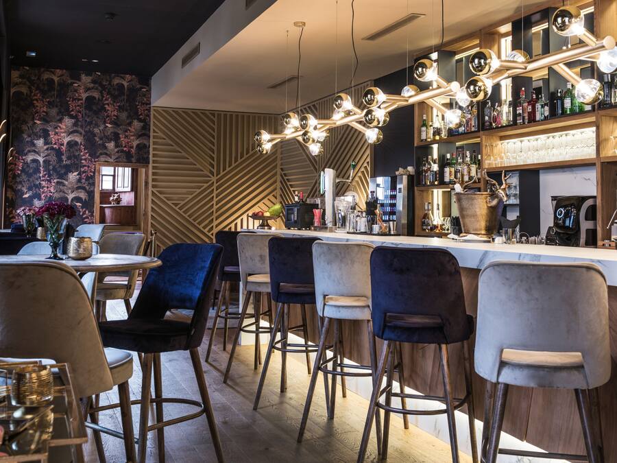 Un espace bar moderne, doté de tabourets, d’un comptoir et d’une variété de bouteilles et de verres.