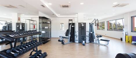 A gym with various exercise equipment, including dumbbells, treadmills, and weight machines.