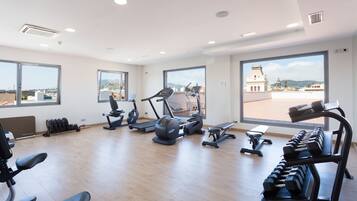 Un gimnasio con máquinas de cardio, pesas y una banca.