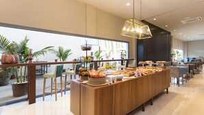 Una barra de desayuno moderna con diversos alimentos, rodeada de asientos y plantas en macetas.