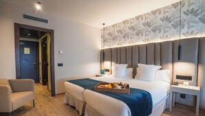 Una habitación de hotel con una cama grande, una mesita de noche, una silla y una bandeja con alimentos para el desayuno.
