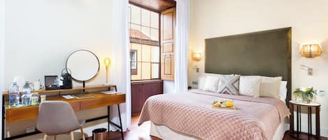 Un dormitorio con un escritorio de madera, una silla y una cama con cabecera acolchada.