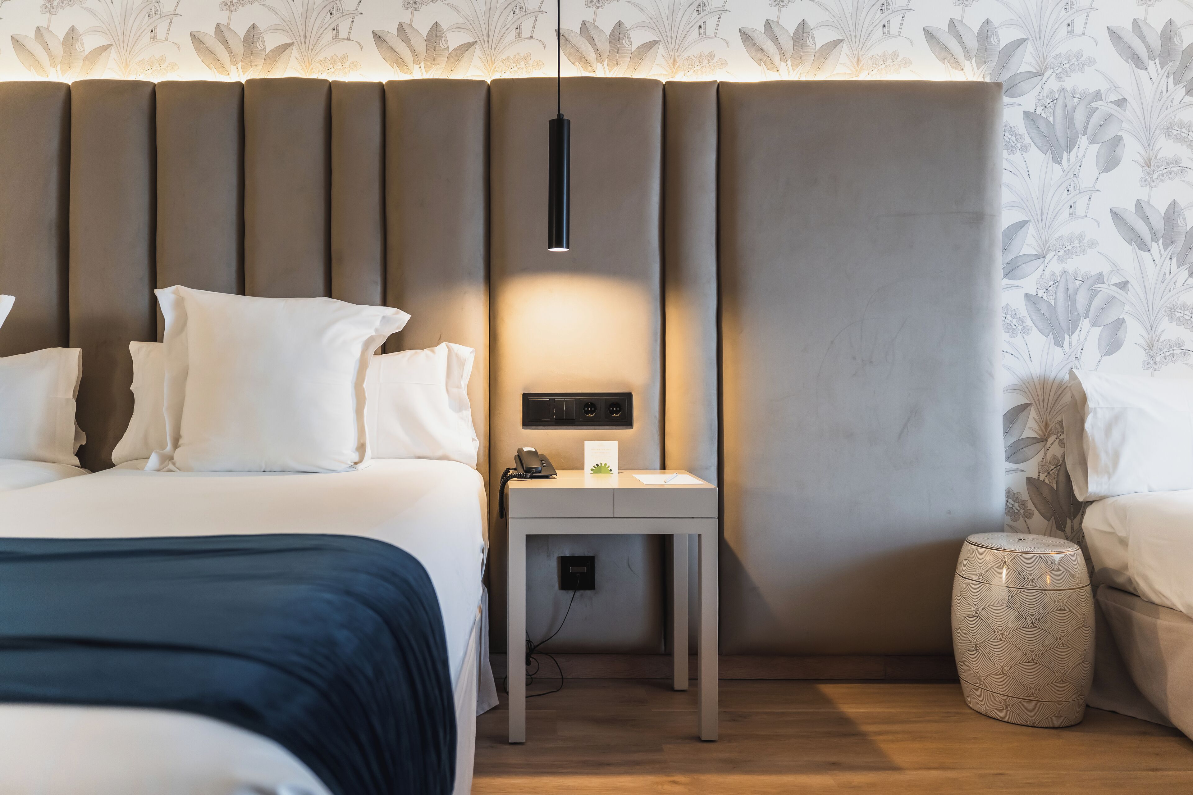 Ein modernes Hotelzimmer mit Bett, Nachttisch, Lampe und dekorativer Vase.