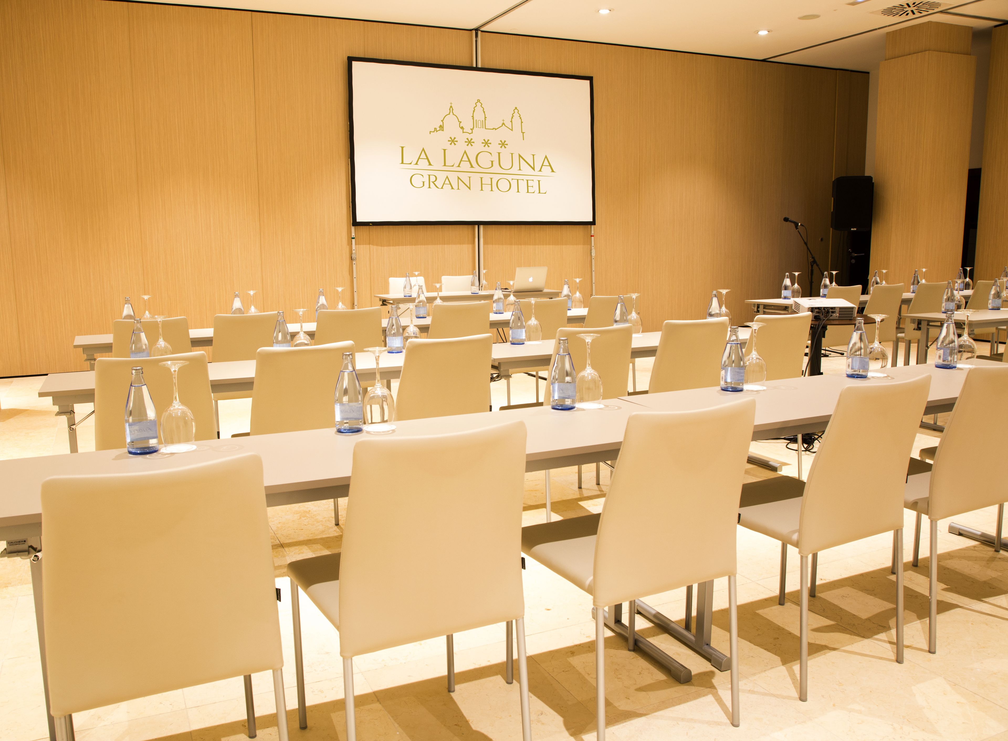 Une salle de conférence à l’hôtel La Laguna Gran, avec des tables disposées pour les réunions, équipée de bouteilles d’eau et de verres.