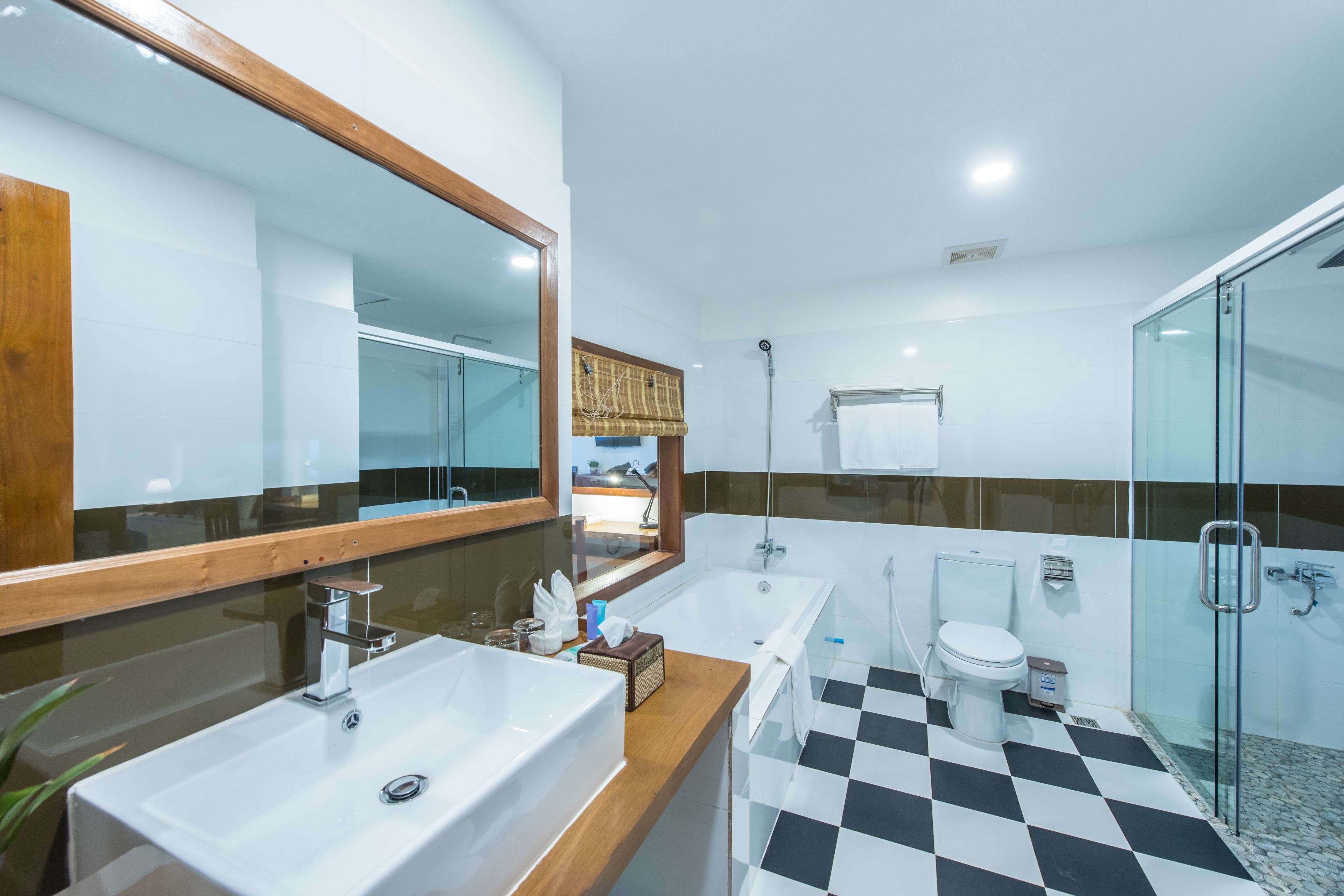 A modern bathroom with a large mirror, two sinks, a bathtub, and a shower.