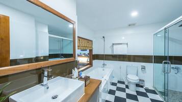 A modern bathroom with a large mirror, two sinks, a bathtub, and a shower.