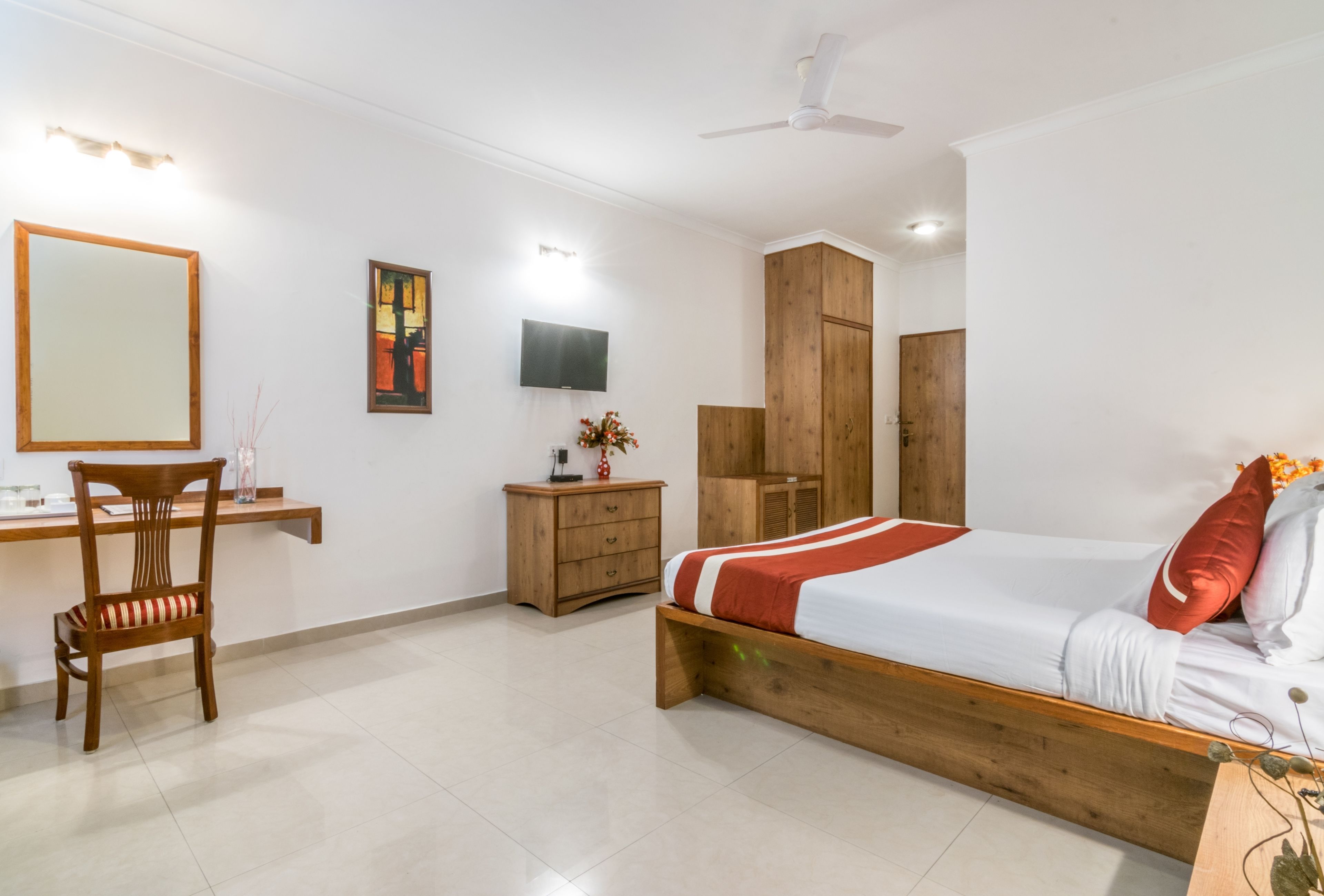Une chambre à coucher avec un lit en bois, un bureau, une chaise, une télévision et une armoire.