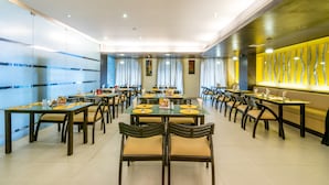 A spacious dining area with multiple tables and chairs, featuring a modern design with glass partitions and a decorative wall. - Octave Hotel Double Rd (Bengaluru)