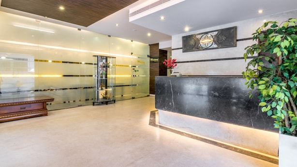 A modern reception area with a marble reception desk, glass walls, and a wooden ceiling. - Octave Hotel Double Rd (Bengaluru)