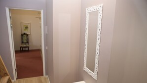 Une salle de bain avec un meuble-lavabo blanc, un miroir doté d’un cadre orné et une chaise en bois à l’arrière-plan.