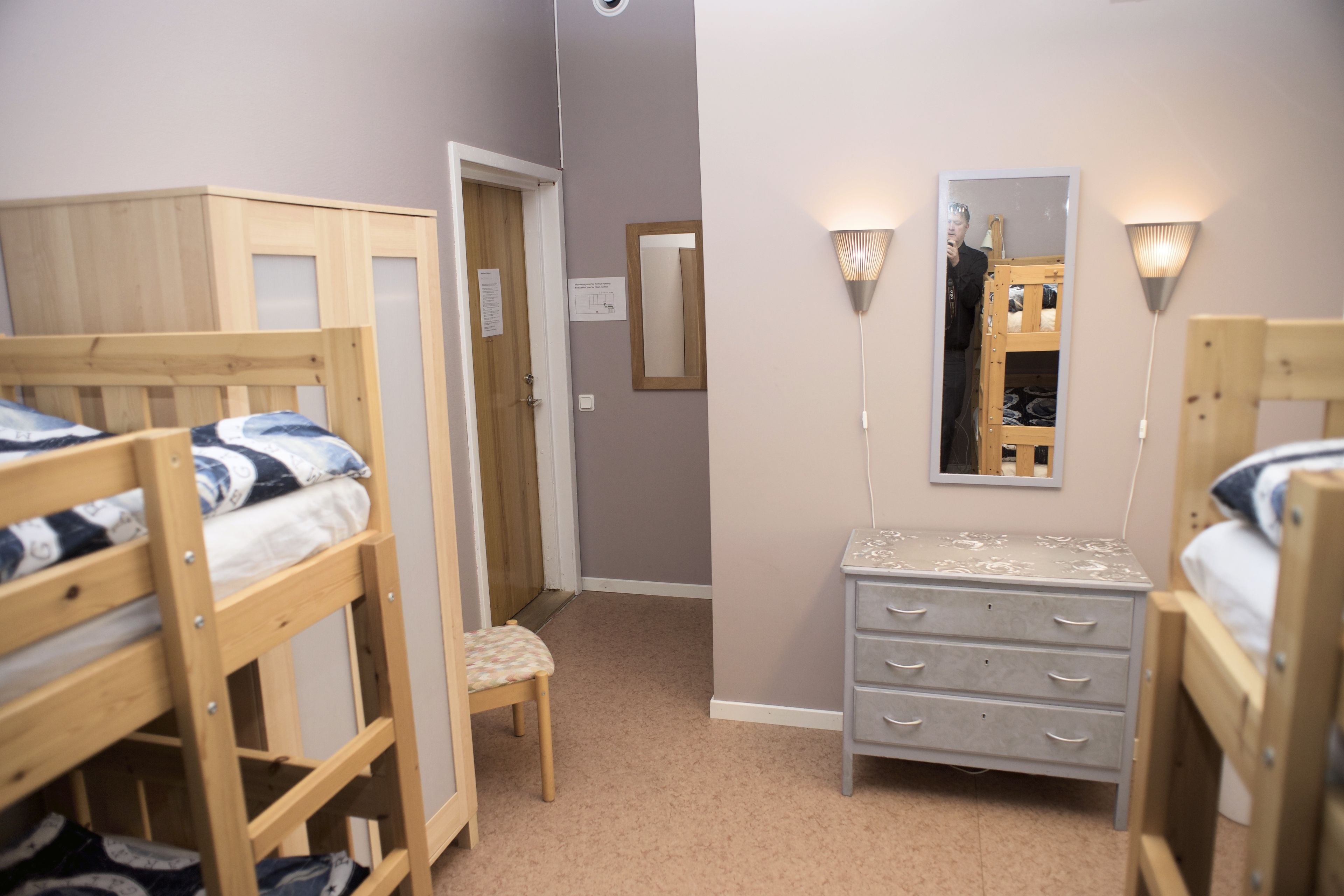 A bedroom with bunk beds, a dresser, a mirror, and two wall-mounted lights.