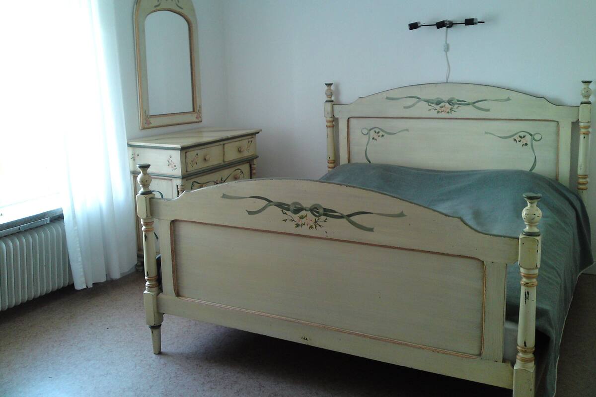 A bedroom with a bed, dresser, and mirror.