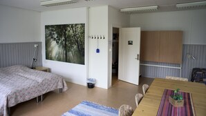 Une chambre avec un lit, une table et une grande fenêtre donnant sur la forêt.