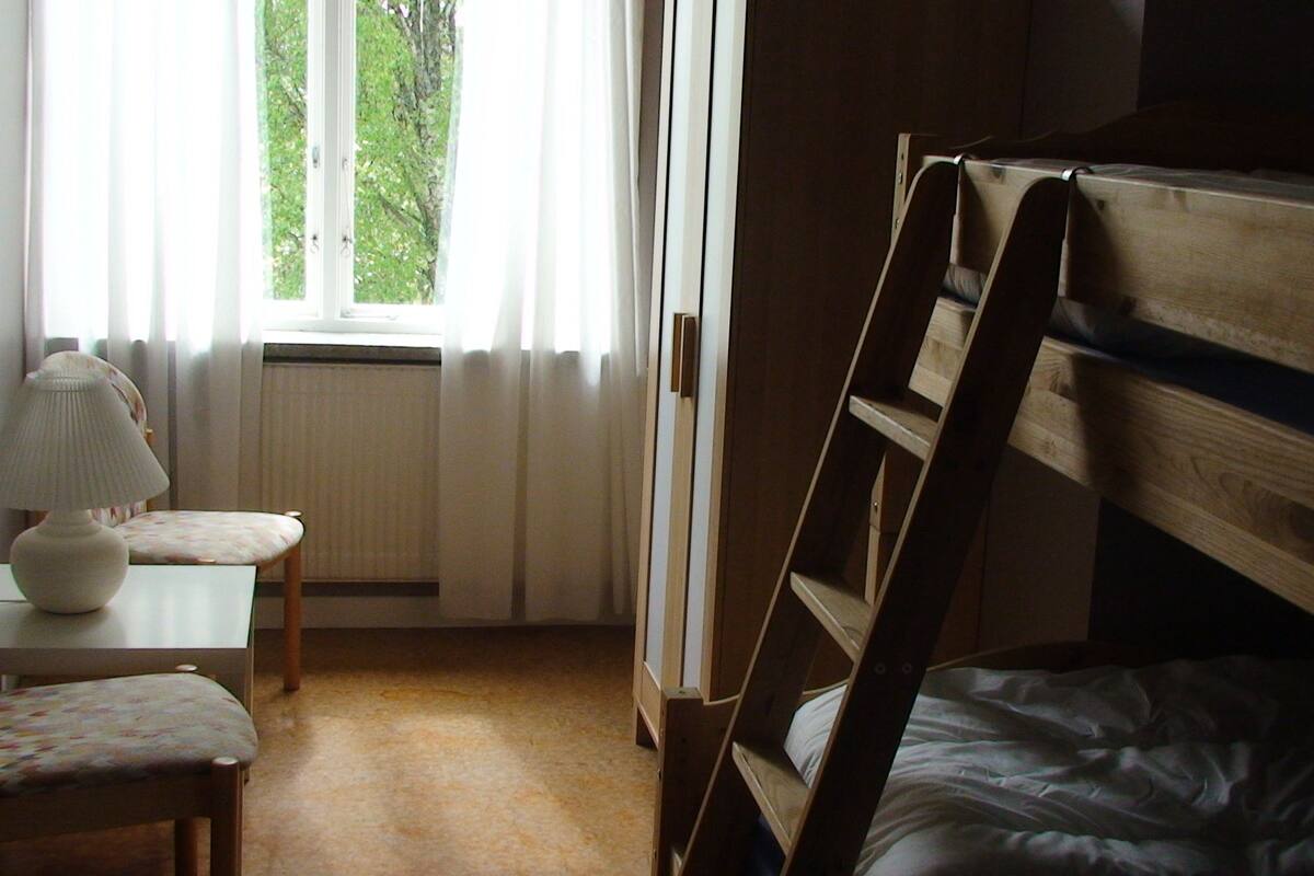 A small, cozy room with a bunk bed, a desk with a lamp, and a chair.