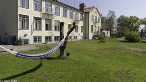 Un bâtiment doté de nombreuses fenêtres et de balcons, un hamac au premier plan et une zone herbeuse.