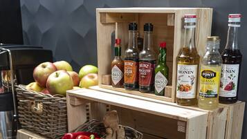A kitchen counter with various food items and condiments, including apples, red bell peppers, carrots, and bottles of sauces.