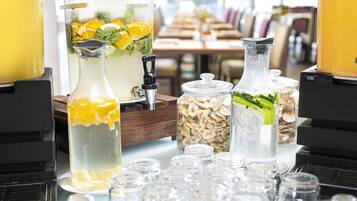 Una mesa con varios recipientes de comida y bebida, incluyendo una jarra con rodajas de naranja y menta, una botella con rodajas de pepino y varios frascos con diferentes ingredientes.