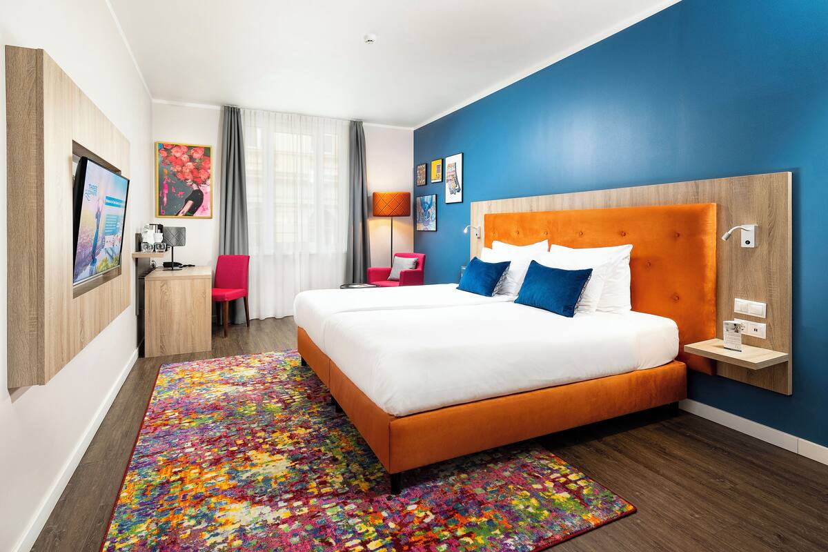 Moderni hotellihuone, jossa on suuri sänky, työpöytä ja tuoli.