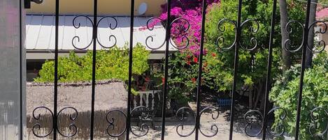 A balcony with a metal railing, a yellow building in the background, and a mountain range.