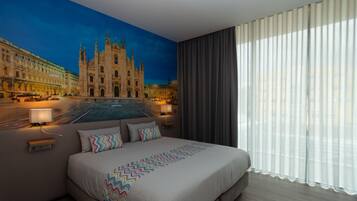 A hotel room with a large bed, a night sky mural, and a view of a historic building.