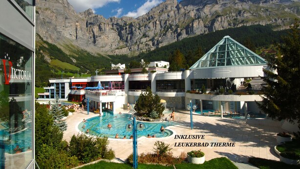 A hotel with a pool, surrounded by mountains.
