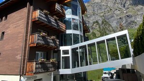 A modern hotel with multiple balconies, large windows, and a view of mountains.