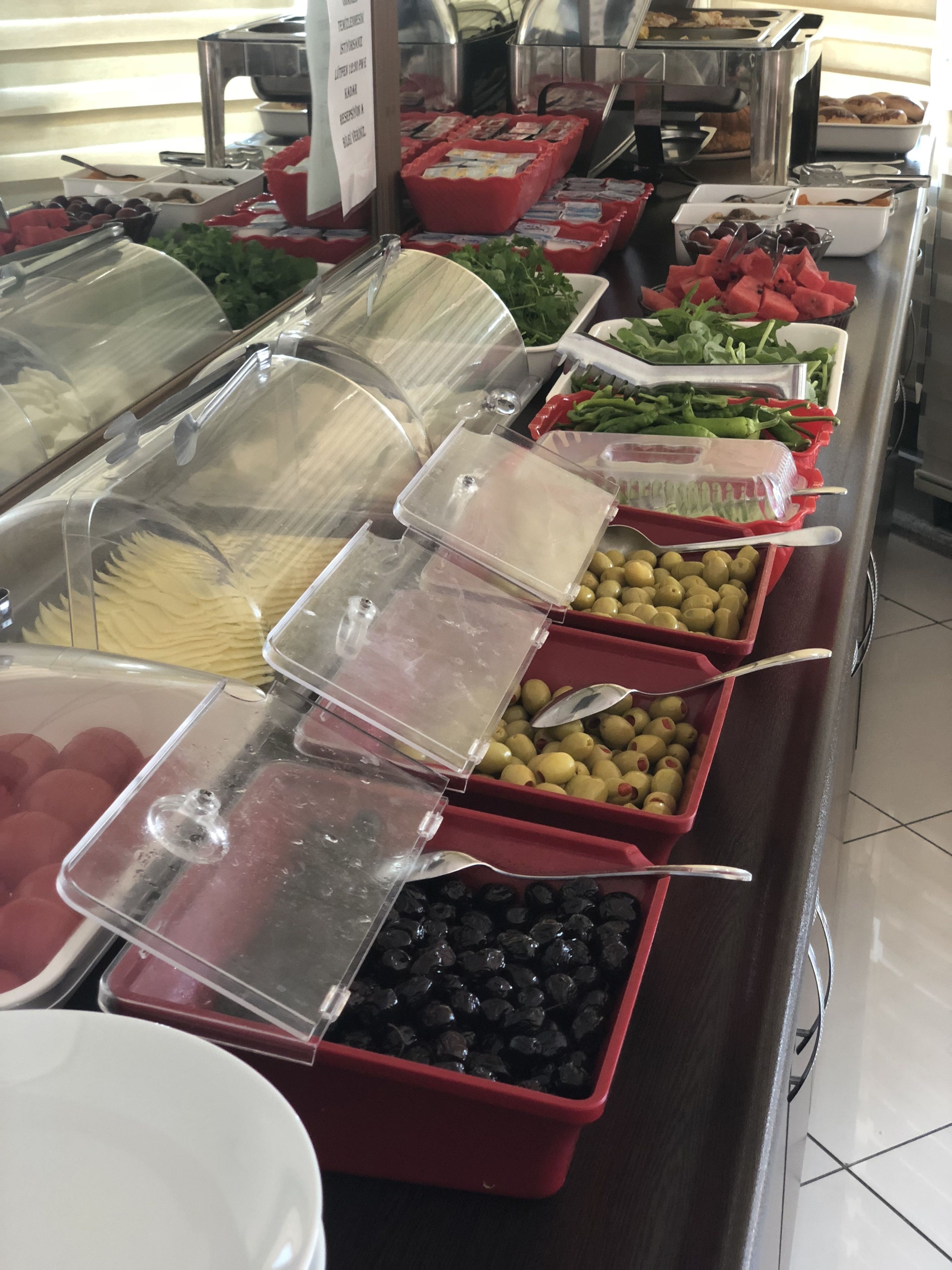Un bufé con diversas opciones de comida, incluyendo frutas, verduras y aceitunas.