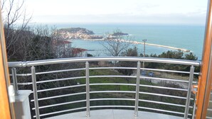 A balcony with a metal railing overlooking a coastal town, a pier, and the sea. - Amasra Ceylin Hotel (Amasra)