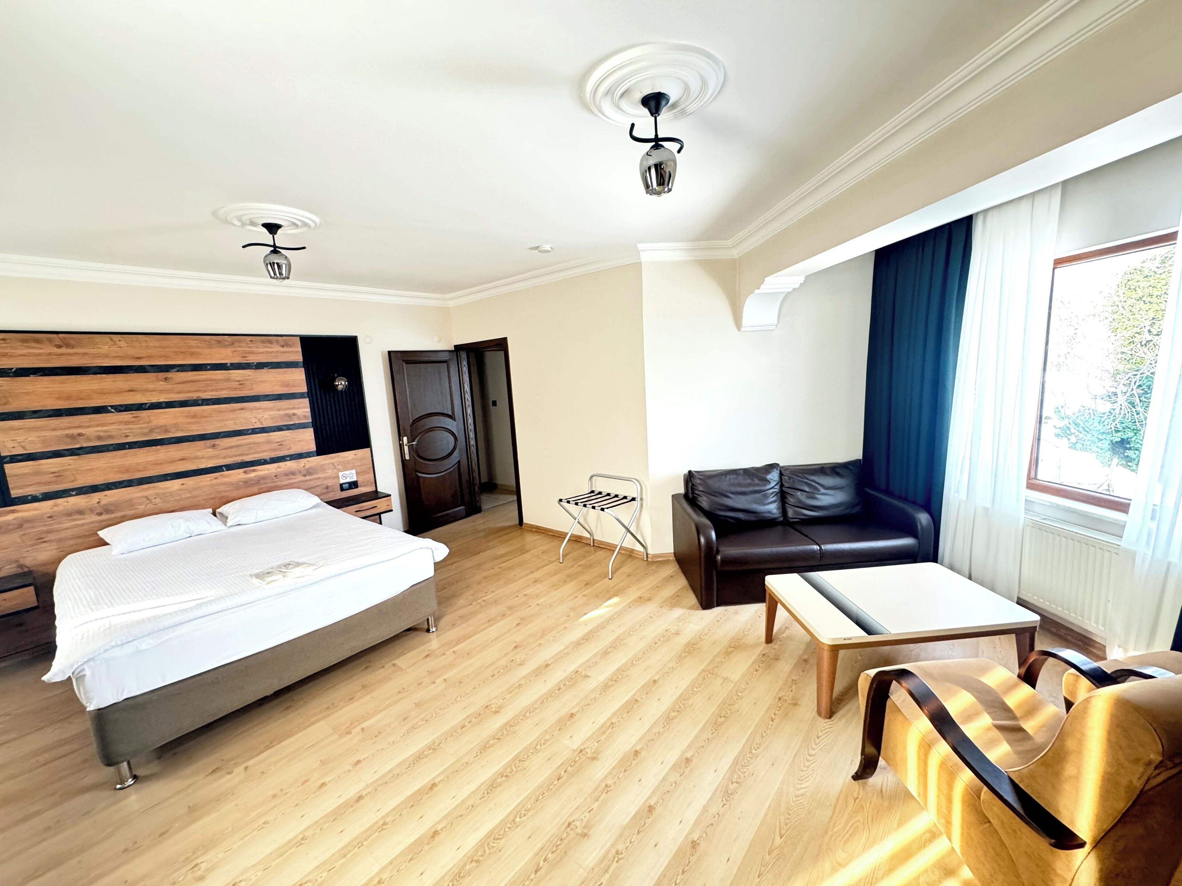 Une chambre d’hôtel avec un lit, un canapé, une table et une fenêtre avec des rideaux.