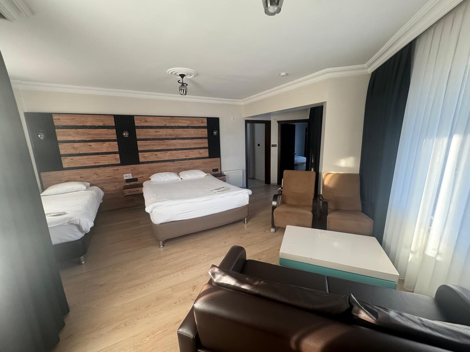 Een hotelkamer met een groot bed, een bank, een bureau en uitzicht op de gang.