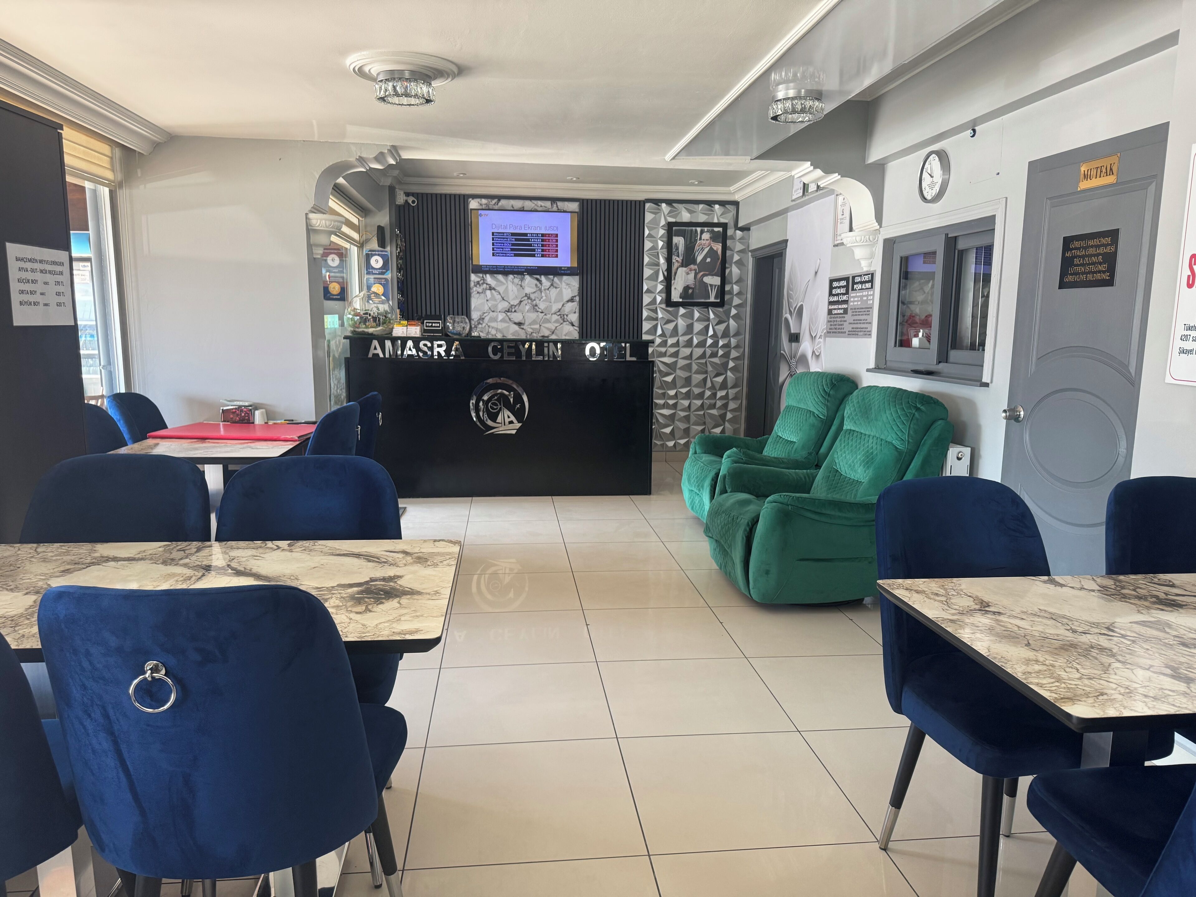 Zona de recepción con mostrador, sillón de masaje verde y asientos azules.