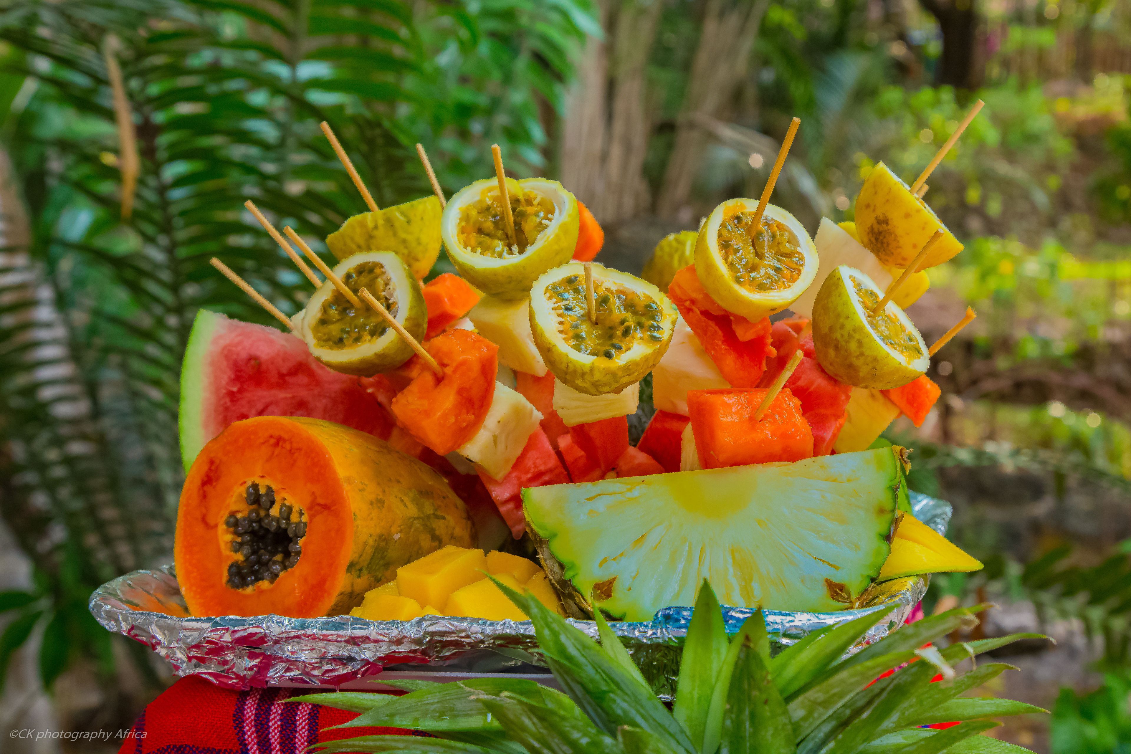 Een fruitschaal met verschillende tropische vruchten en prikkertjes.