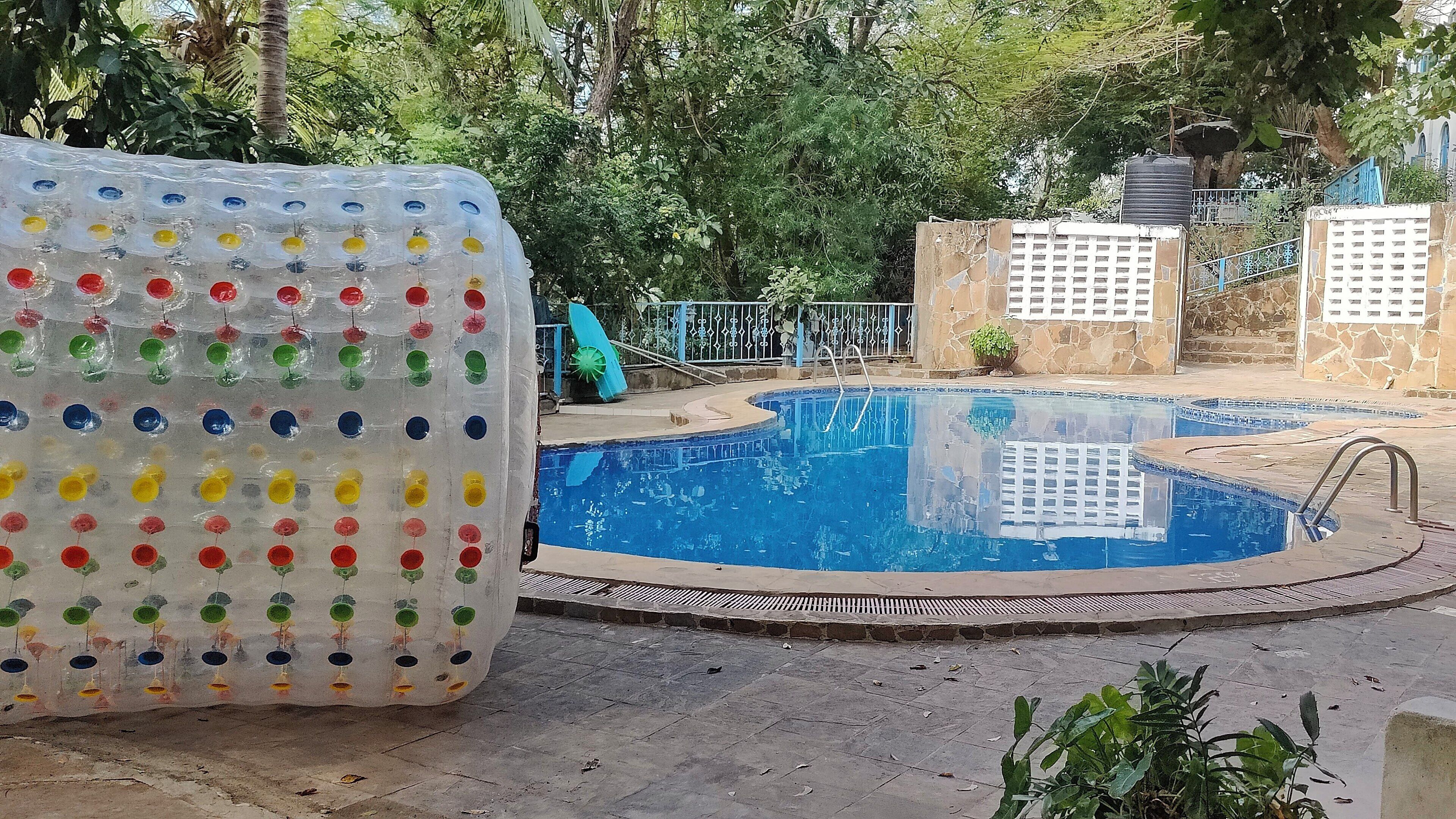 A swimming pool with a stone wall and a metal gate.