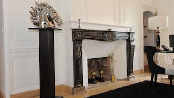 A room with a fireplace, a black stand with a silver sculpture, and a black chair.