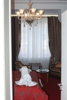 Una habitación de hotel con cama, dos sillones, una mesita y una araña.