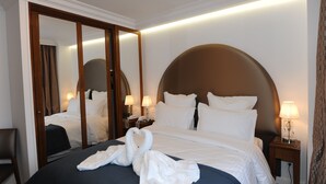 Una habitación de hotel con una cama grande, dos lámparas de noche, un espejo y un cabecero de madera.