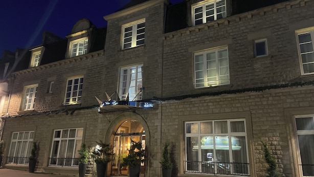 Un edificio de piedra con un amplio arco de entrada, varias ventanas y un letrero que indica que es un hotel.