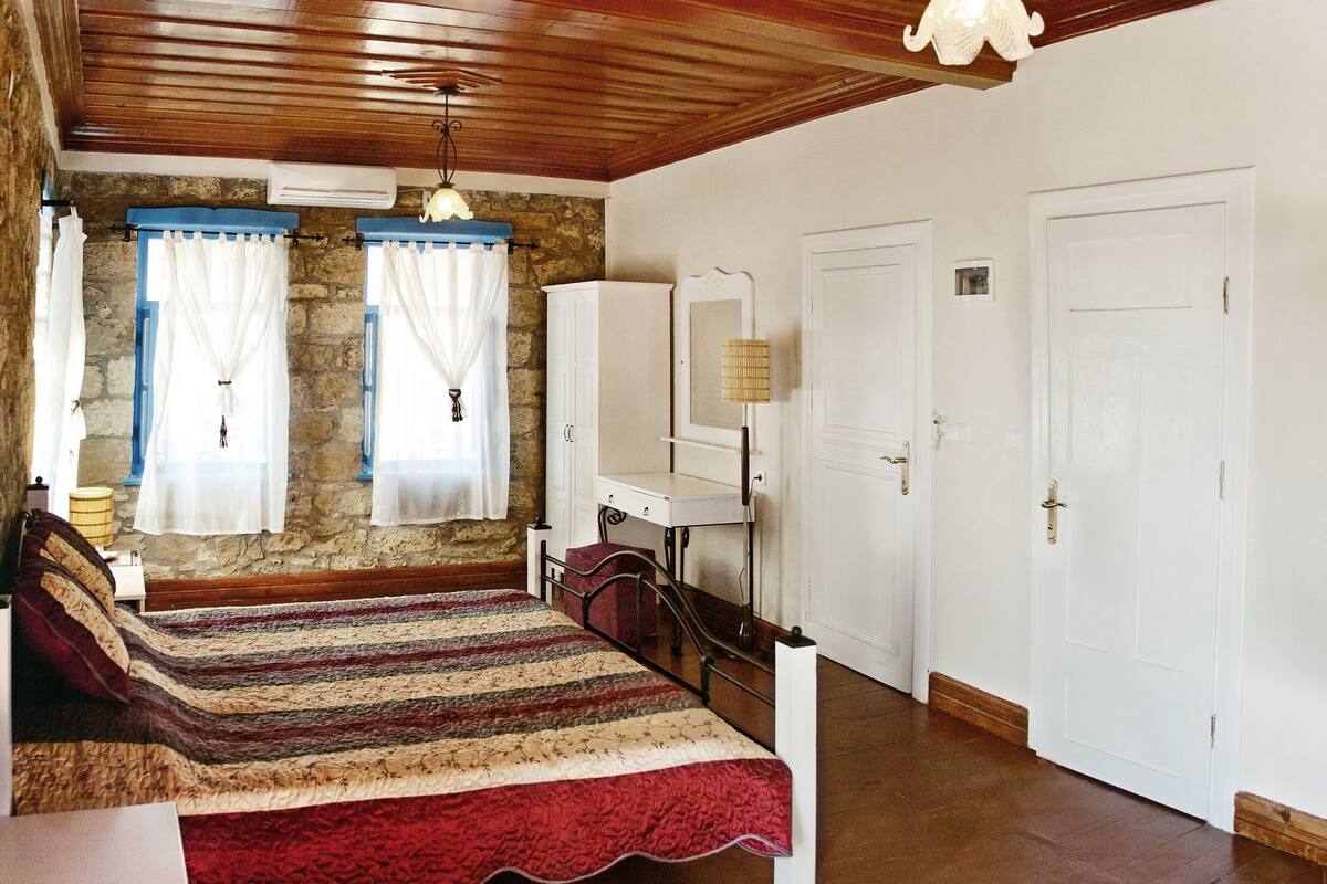 A bedroom with a bed, a desk, a mirror, and a wardrobe.