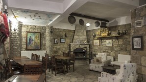A rustic interior with stone walls, a fireplace, wooden furniture, and various framed artworks. - Hunnaphan Otel (Ayvacik)