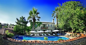 Una piscina al aire libre, sombrillas, sillones reclinables de piscina