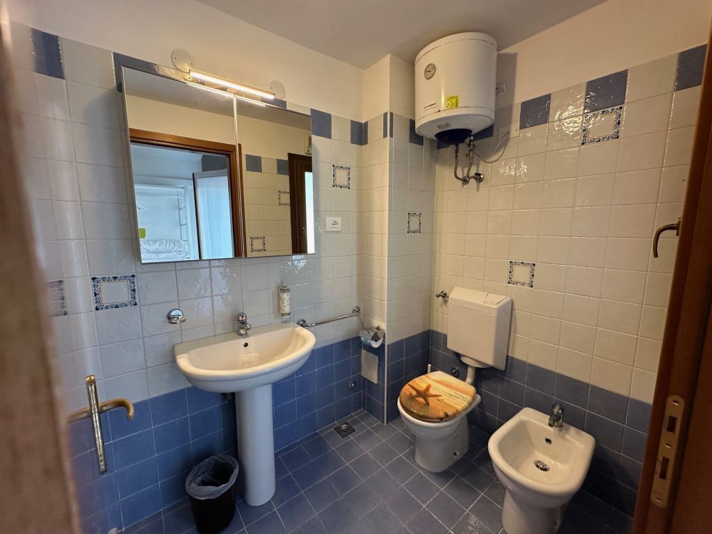 Un baño con lavamanos, inodoro, bidé y espejo.