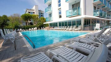 Ein moderner Poolbereich mit weißen Liegestühlen und einem klaren, blauen Pool.