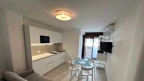 A compact living space with a kitchenette, a dining area, and a sofa.