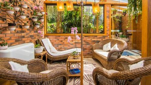 A room with wicker furniture, a brick wall, and potted plants. - Hotel Azaleia (Gramado)