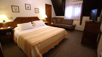 Una habitación de hotel con una cama grande, un sofá, un televisor y un escritorio con lámpara.