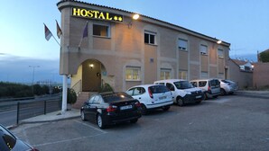 A building with a sign reading "HOSTAL" and several parked cars in front. - Hostal 82 (Olias del Rey)