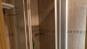 A shower enclosure with a glass door, a showerhead, and a tiled floor.