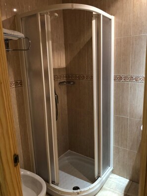 A shower enclosure with a glass door, a showerhead, and a tiled floor.